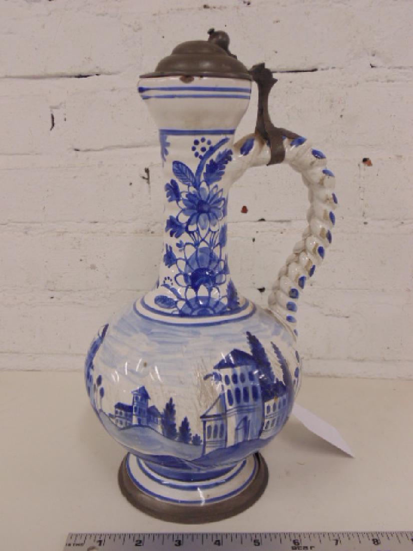 Delft porcelain ewer, blue & white, pewter lid: Delft porcelain ewer, blue & white, pewter lid, decorated with houses, height is 12.5", some scratches, minor chips rim also pewter knob is bend inward