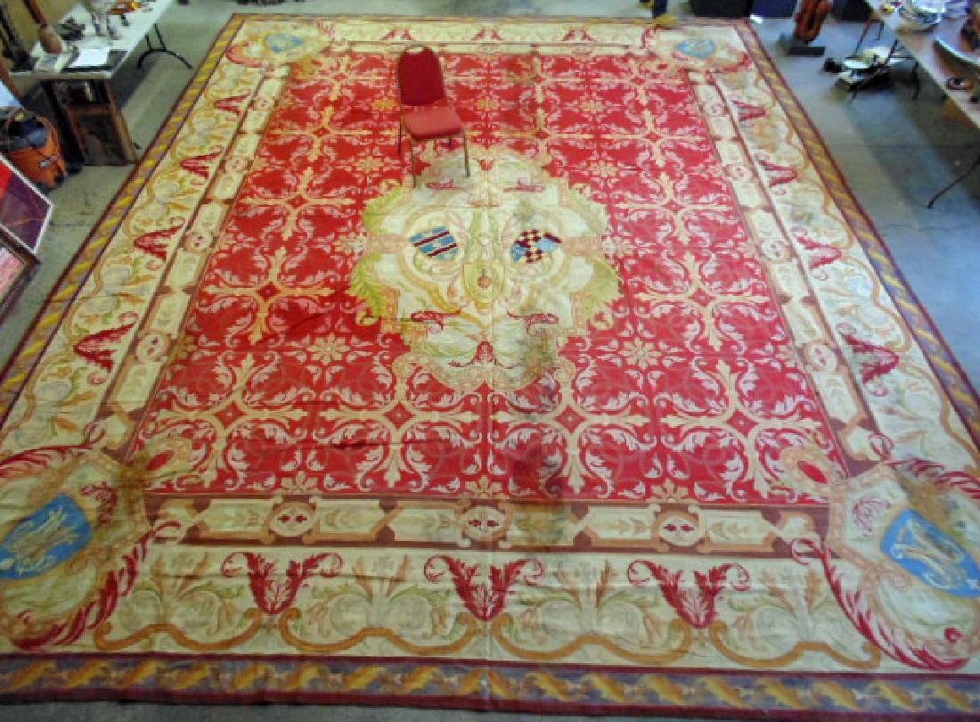 Palace size Aubusson needlepoint rug, coat of arms in: Palace size Aubusson needlepoint rug, coat of arms in center, each corner has shield with letter, red field with beige border, rug is 23' by 18'10", rug has water damage.this rug was cleaned and a new