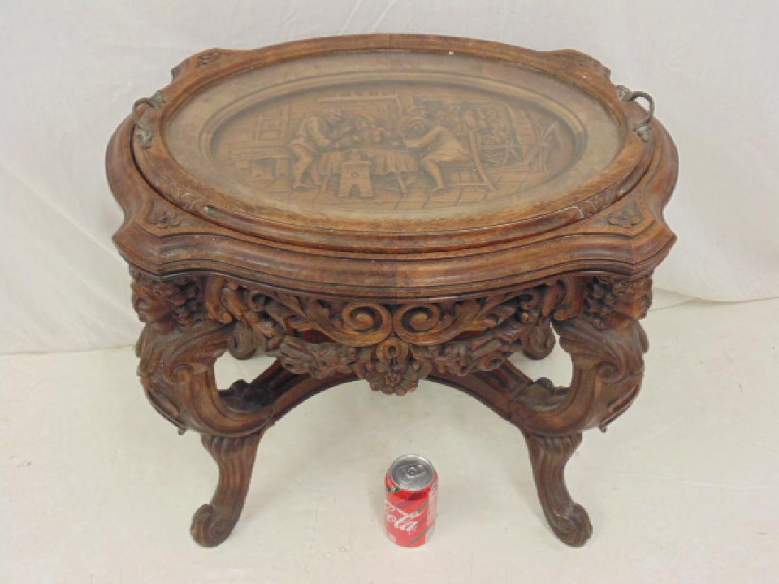 Carved side table with tray top, top of table has: Carved side table with tray top, top of table has carved tavern scene, winged angels as legs, finish is distressed, table is 18.5" by 24" height is 20.5"