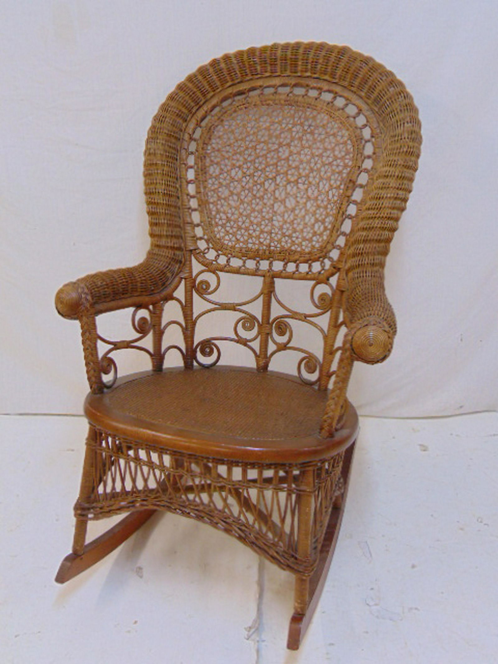 Wicker rocker, natural brown finish rocker with woven: Wicker rocker, natural brown finish rocker with woven seat, caned back & decorative curls.