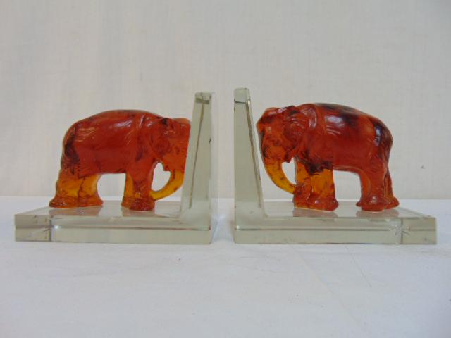 Pair glass elephant bookends by Heinrich Hoffmann,: Pair glass elephant bookends by Heinrich Hoffmann, amber glass elephants on clear glass bookend bases, each base is 6.5" by 4", height is 5.25", few small chips on clear glass, one elephant has small