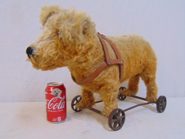 Dog pull toy, dog mounted on iron base with wheels, fur: Dog pull toy, dog mounted on iron base with wheels, fur worn on his back, has original leather harness, base is 12" by 8", height is 13"