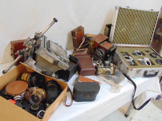 Large lot vintage camera equipment, various old cameras: Large lot vintage camera equipment, various old cameras including Bolsey Model C, Argus, old brass lenses, parts of enlarger, alu case with Nikkormat cameras & more, all in as is condition.