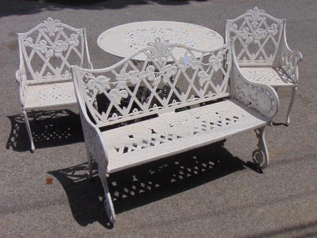 Aluminum & zinc patio set, round table, pair chairs &: Aluminum & zinc patio set, round table, pair chairs & bench, in white paint, decorated with grapes & leaves, table is 42" in diameter, bench is 48" long, chairs are 21" wide.