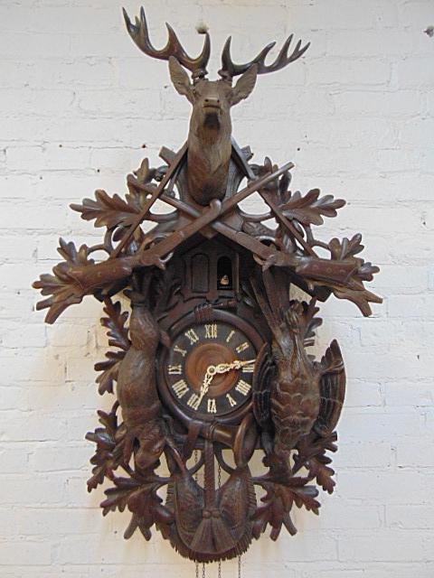 Large black Forest cuckoo clock with hunt themed: Large black Forest cuckoo clock with hunt themed carvings, pheasant, rabbit, crossed rifles and deer finial, with pine cone weights, clock is 40" tall, minor loss, one of the pop out figures is missin