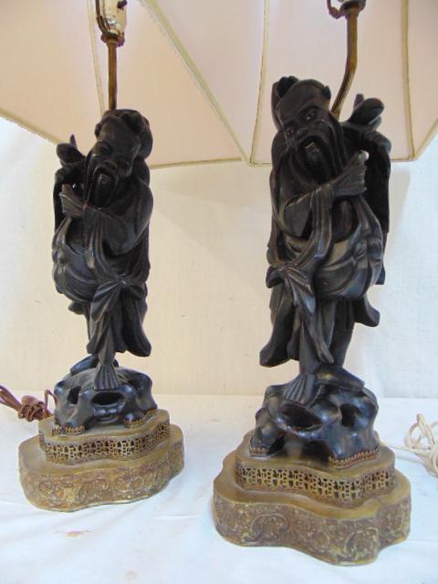 Pair carved wood Chinese figural lamps, ebonized on: Pair carved wood Chinese figural lamps, ebonized on brass bases, each lamp is 16.5" tall, excluding socket extension, with original shades.