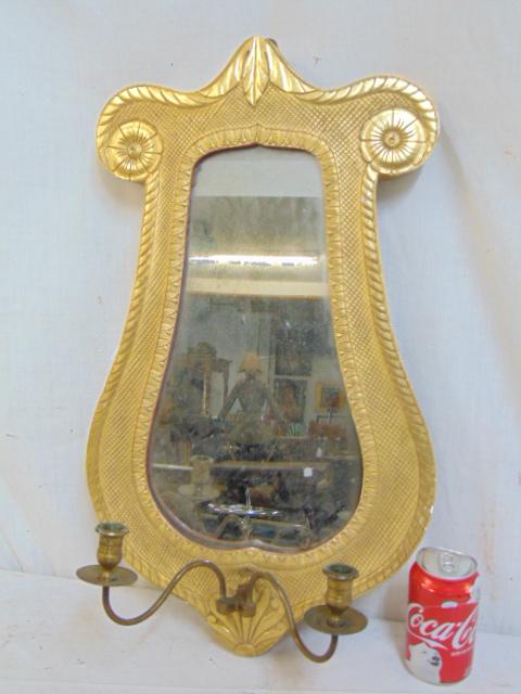 Antique shield mirror sconce, gilt wood mirror with: Antique shield mirror sconce, gilt wood mirror with carved detail & scrolled top with brass double arm candle holder, 24" by 14"