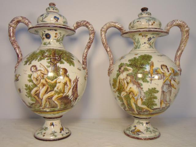 Pair glazed terra cotta urns, Majolica style, Adam &: Pair glazed terra cotta urns, Majolica style, Adam & eve scenes, handled urns with lids, each urn is hand painted with various scenes of Adam & Eve, urns are 16.25" tall, some glaze chips, one urn has