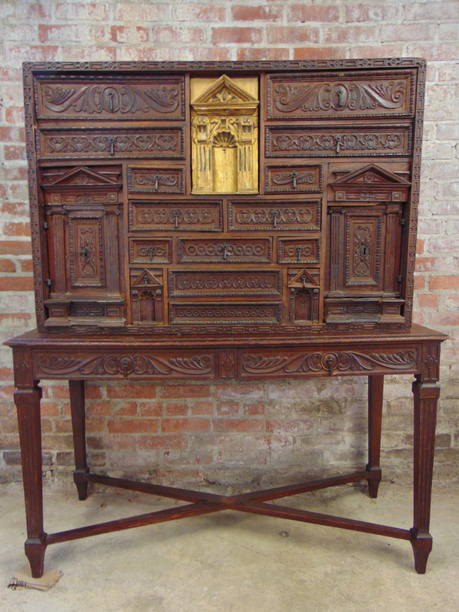 17th Century Spanish Vargueno, elaborated carved front with carved drawers, some with locking: 17th Century Spanish Vargueno, elaborated carved front with carved drawers, some with locking mechanisms, gilt center drawer pulls out to reveal hidden compartments, on later base, with iron handles, 