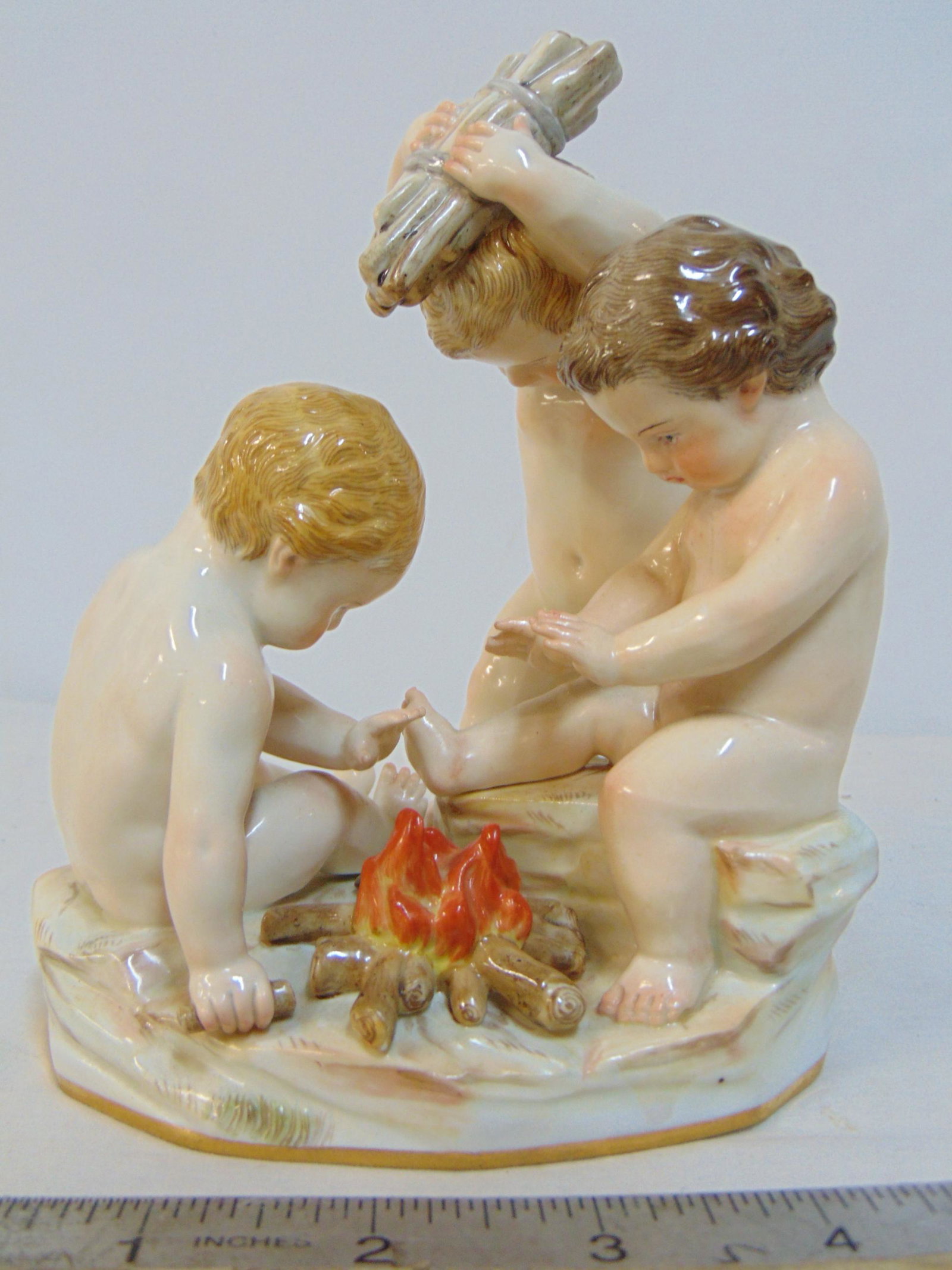 Meissen porcelain group, putti building fire, 3 putti around a small fire, one holding wood, crossed: Meissen porcelain group, putti building fire, 3 putti around a small fire, one holding wood, crossed sword mark, good condition, no chips, cracks or repairs, height is 5.75"