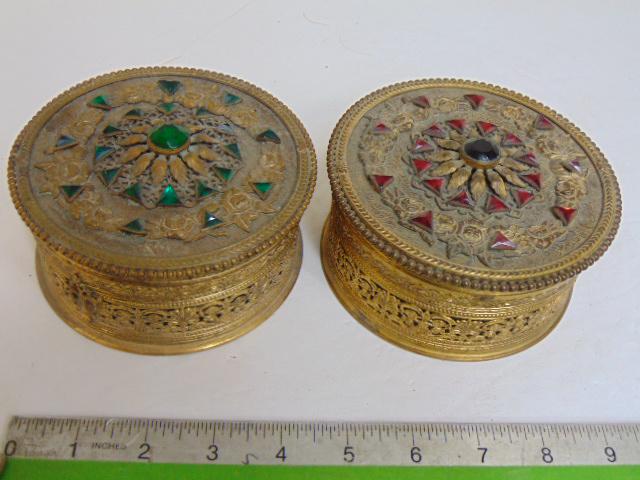 2 Apollo round jeweled powder boxes with glass inserts, one with green, the other with red glass: 2 Apollo round jeweled powder boxes with glass inserts, one with green, the other with red glass stones, 4.75" in diameter.