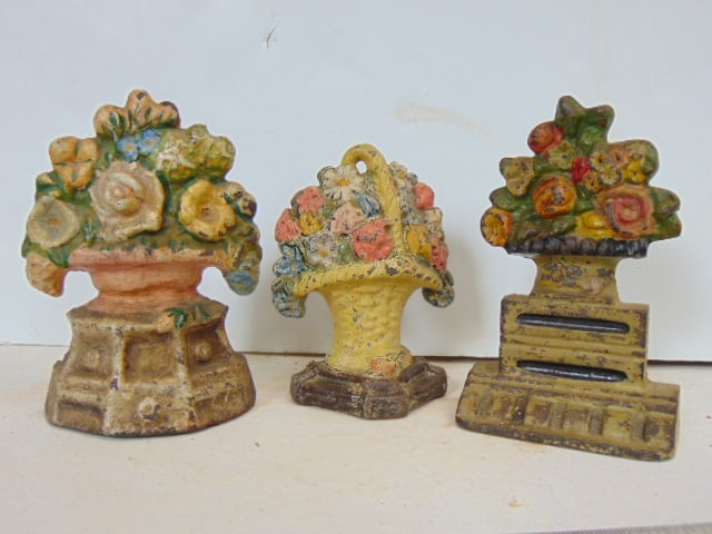 3 cast iron doorstops, flowers in urns, 6.5" tall (two) & one smaller one, 5.75" (1 of 4)
