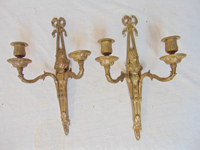 Pair bronze double arm candle sconces with figural features, each sconce is 15.75", one sconce is: Pair bronze double arm candle sconces with figural features, each sconce is 15.75", one sconce is missing a candle cup