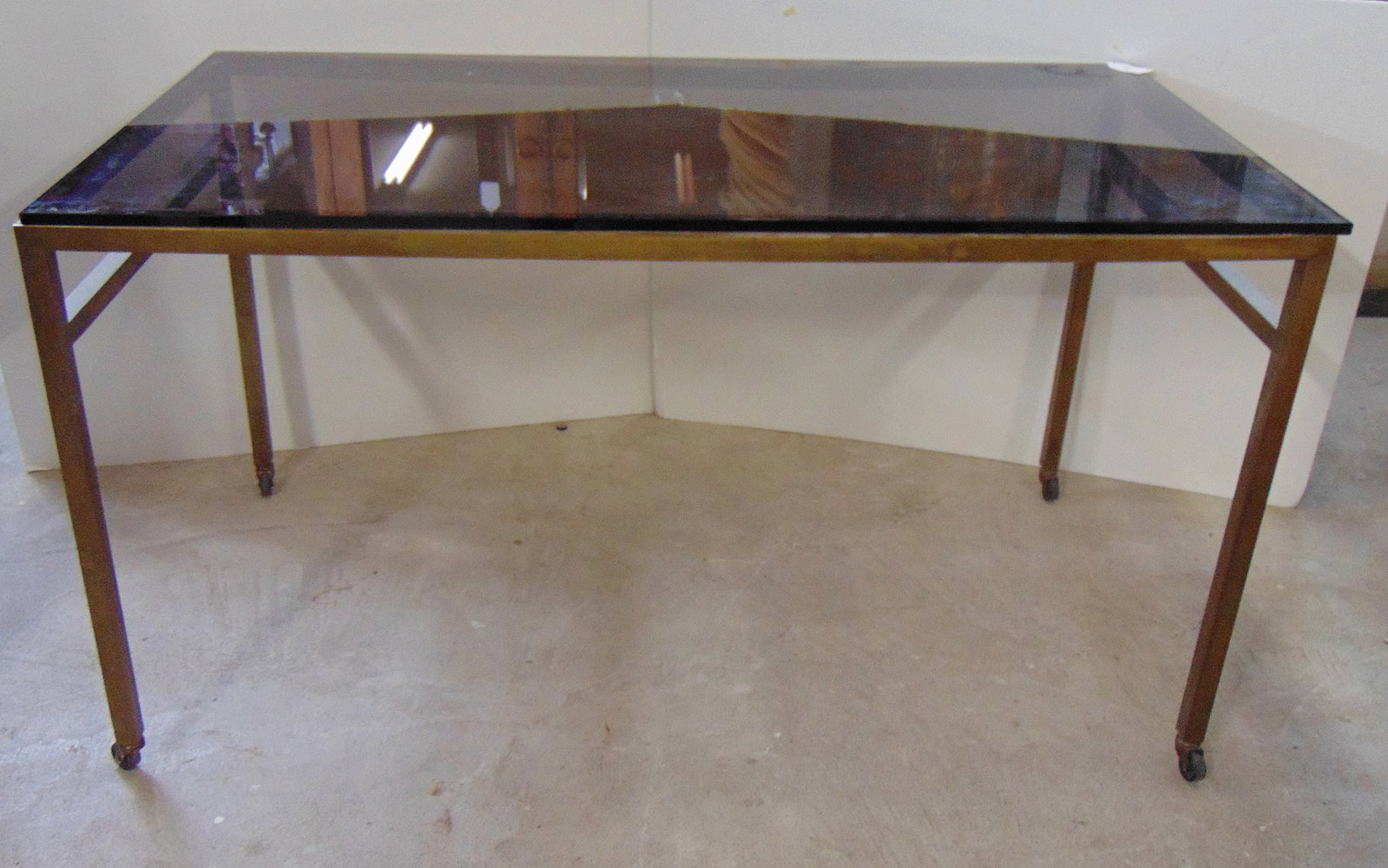 Brass base smoky glass top dining table, top is 57" by 30", height is 30.75", glass is chipped one: Brass base smoky glass top dining table, top is 57" by 30", height is 30.75", glass is chipped one one corner