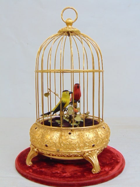 Automaton birds in gilt cage, red & yellow bird, comes with glass dome, movement works, but makes no: Automaton birds in gilt cage, red & yellow bird, comes with glass dome, movement works, but makes no sound, bellows need work, height (dome ) is 12.5"