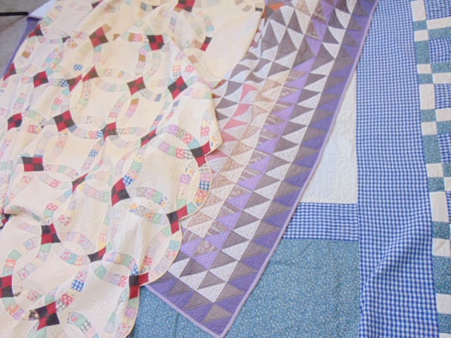 3 quilts, blue block pattern, geometric with triangles & white with circular pattern.white quilt is (1 of 5)