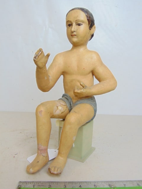 Carved wood figure of a seated boy, glass eyes, fingers missing on right hand, repair to legs,: Carved wood figure of a seated boy, glass eyes, fingers missing on right hand, repair to legs, height is 12.5"