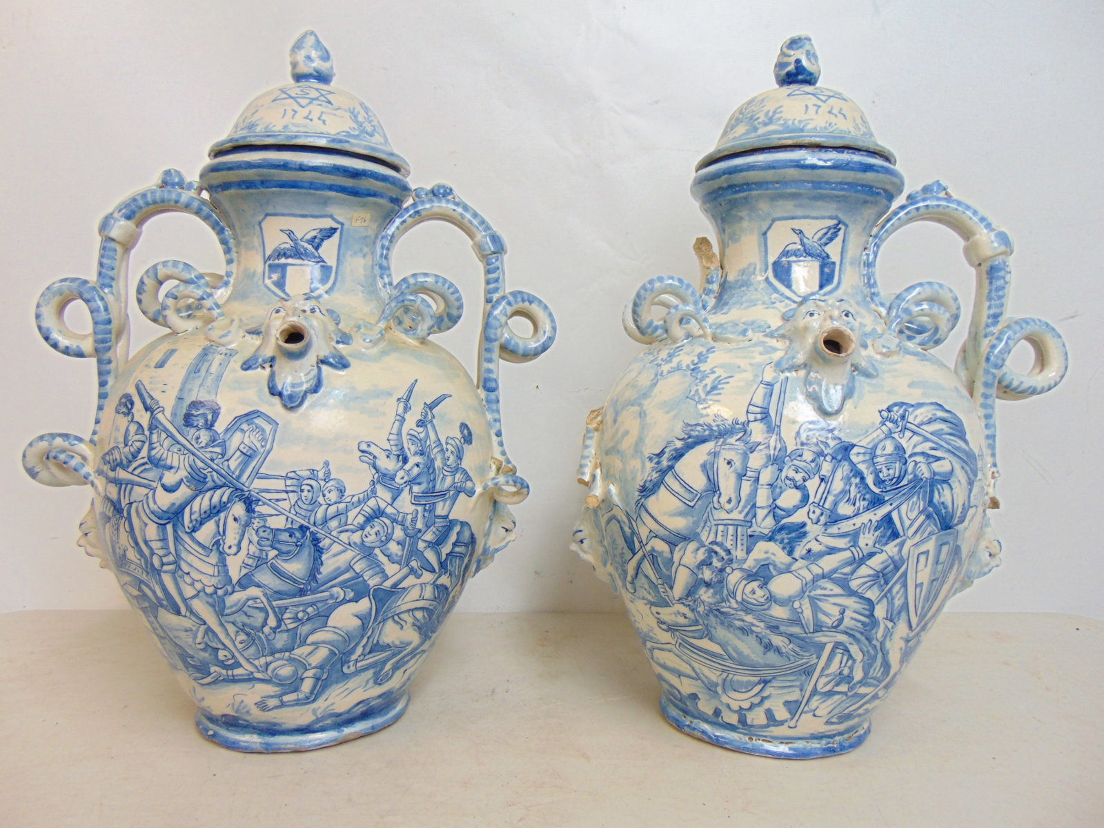 2 large Italian Faience Majolica wine jugs with battle scenes & elegant snake lake handles, both: 2 large Italian Faience Majolica wine jugs with battle scenes & elegant snake lake handles, both lids have star with 1744 below it, one handle missing, and some loss on handles, height is 20.75".