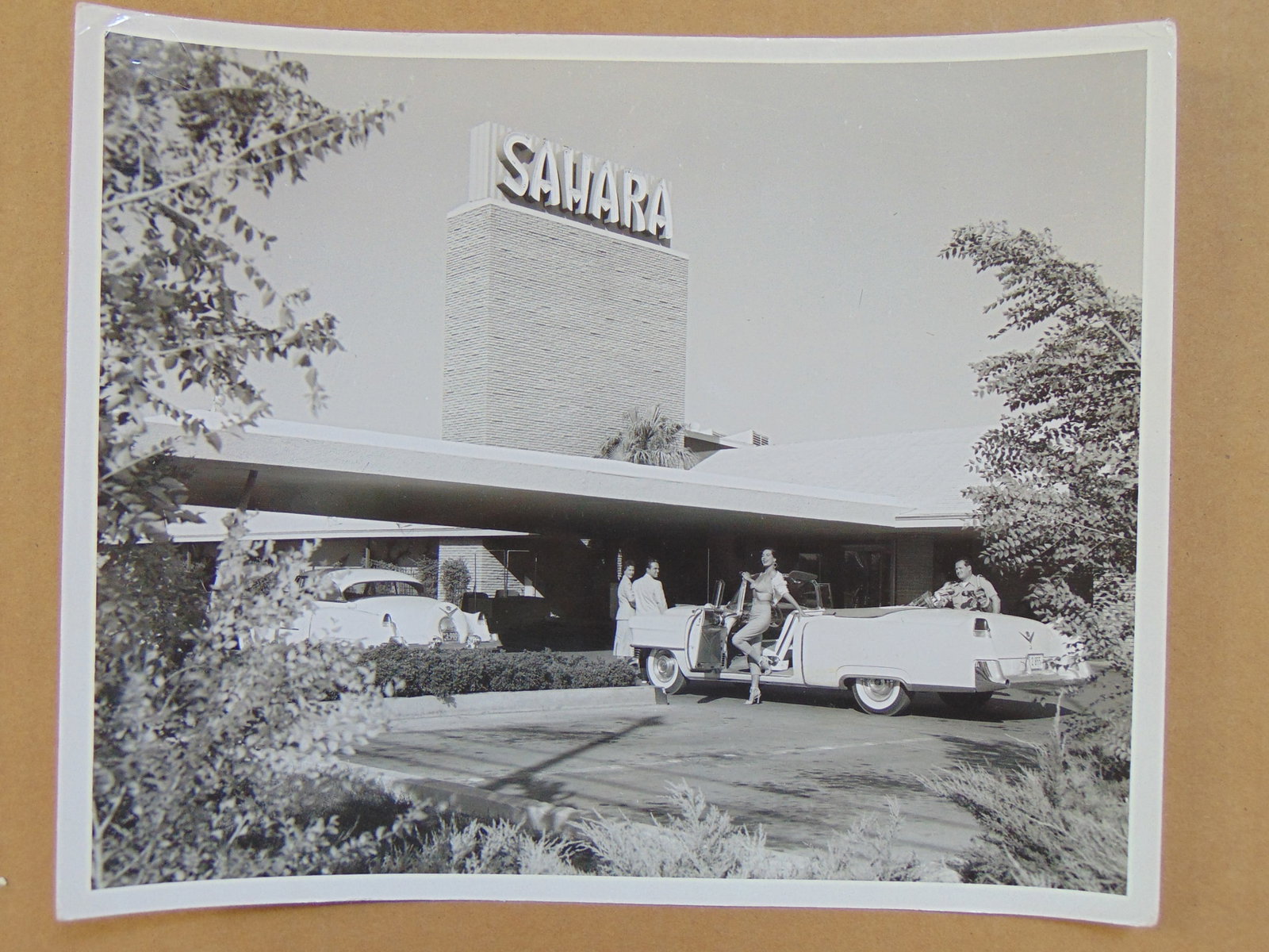 Photograph, Las Vegas News Bureau, Don English-Joe Buck-Jerry Abbott, "So hat man sich die wuste: Photograph, Las Vegas News Bureau, Don English-Joe Buck-Jerry Abbott, "So hat man sich die wuste Sahara nicht vorgestelt", woman in heels exiting a large car in front of Sahara hotel, 8" by 10", with 
