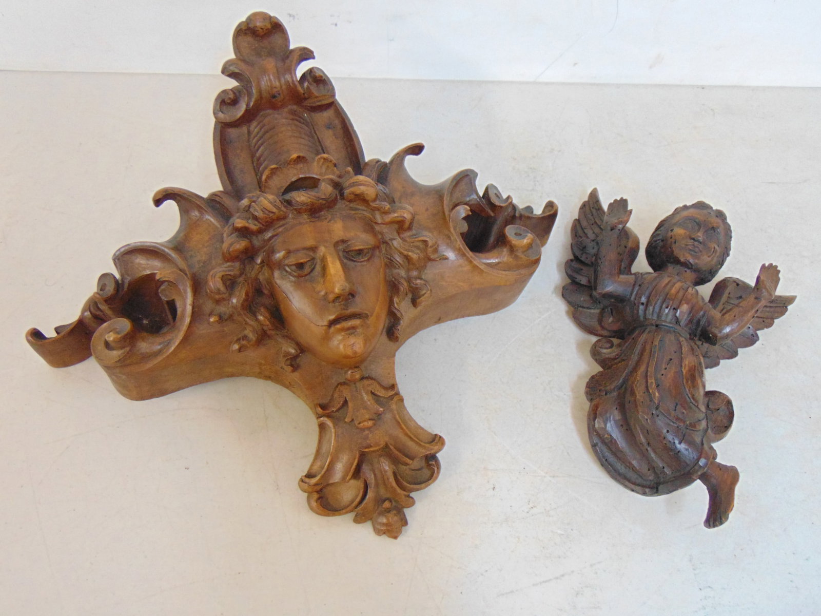 2 wood carvings, winged angel & carved figural crest, angel is 11" tall, crest is 14.5" tall, 16": 2 wood carvings, winged angel & carved figural crest, angel is 11" tall, crest is 14.5" tall, 16" wide.