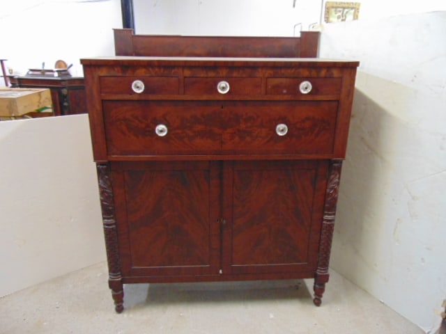 Empire mahogany chest of drawers with decorative half columns & back splash, left door has damage by: Empire mahogany chest of drawers with decorative half columns & back splash, left door has damage by upper hinge, needs repair, chest is 46.5" by 23.5", height is 58.25"