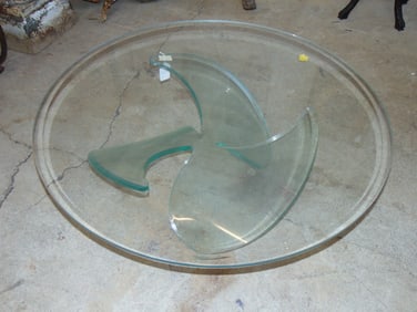 Glass top coffee table on Lucite base, base shaped like a boat propeller, top table is 42"
