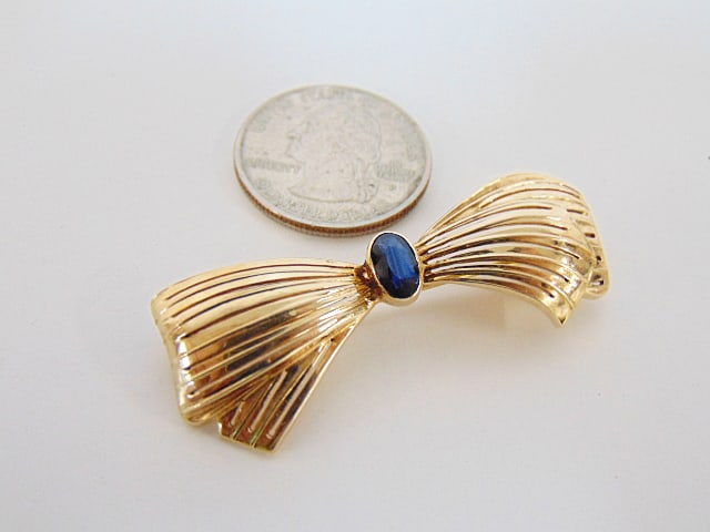 Jewelry. 14kt Gold bow pin, 6.60 grams with oval bezel set sapphire, approx. 4mmx7mm, hallmark 14kt,: Jewelry. 14kt Gold bow pin, 6.60 grams with oval bezel set sapphire, approx. 4mmx7mm, hallmark 14kt, 22-166, good condition.