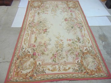Needlepoint rug with floral pattern, pink border, carpet is 8'11" by 5'10"