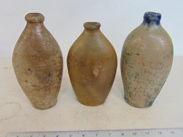 3 small stoneware bottles, one has green paint with blue highlights around neck, height ranges from (1 of 4)