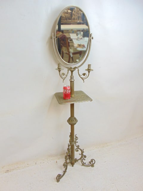 Standing brass shaving or vanity mirror with two candle holders, oval mirror, decorative base, one: Standing brass shaving or vanity mirror with two candle holders, oval mirror, decorative base, one leg broken, needs repair, height is 63.5"