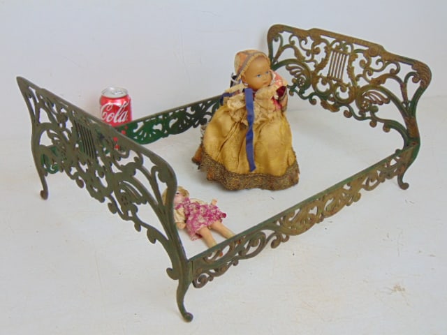 Early iron doll bed with two small dolls, bed is 22" by 15.5", tall doll is 10" tall in vintage: Early iron doll bed with two small dolls, bed is 22" by 15.5", tall doll is 10" tall in vintage clothing.