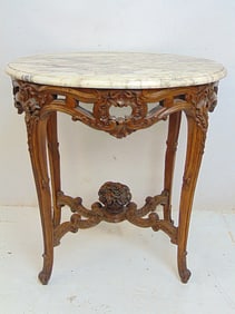 Marble top table with ornately carved wood base, carved fruit basket on carved cross stretcher base,