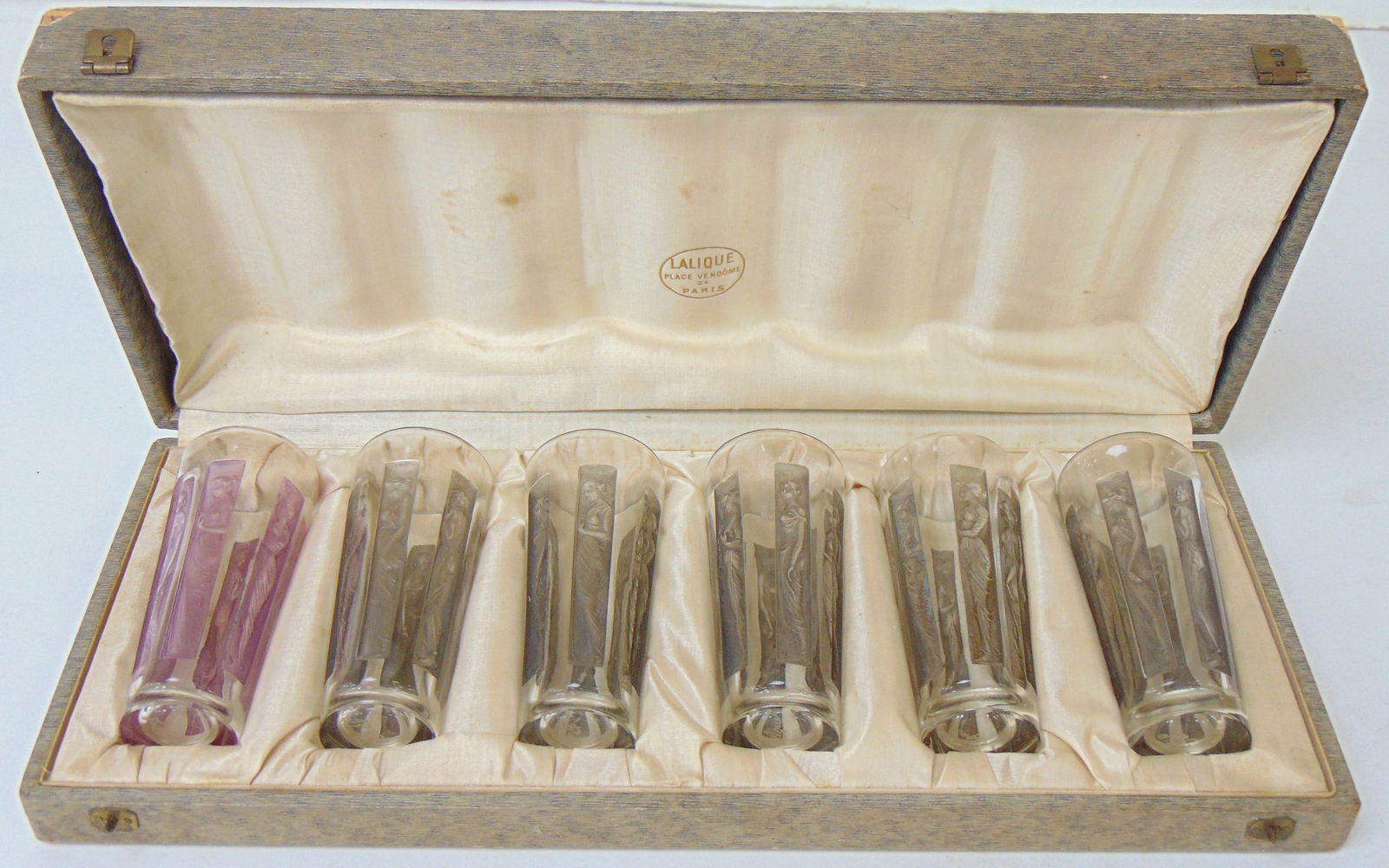 Rare set Lalique 6 figurines goblets in original case, circa 1930: Vintage Lalique 6 figurines glass goblets in original box, circa 1930, one pink, 5 grey tinted, all signed R. Lalique, each glass is 4" tall, one glass (grey), has small chip on rim, otherwise all in