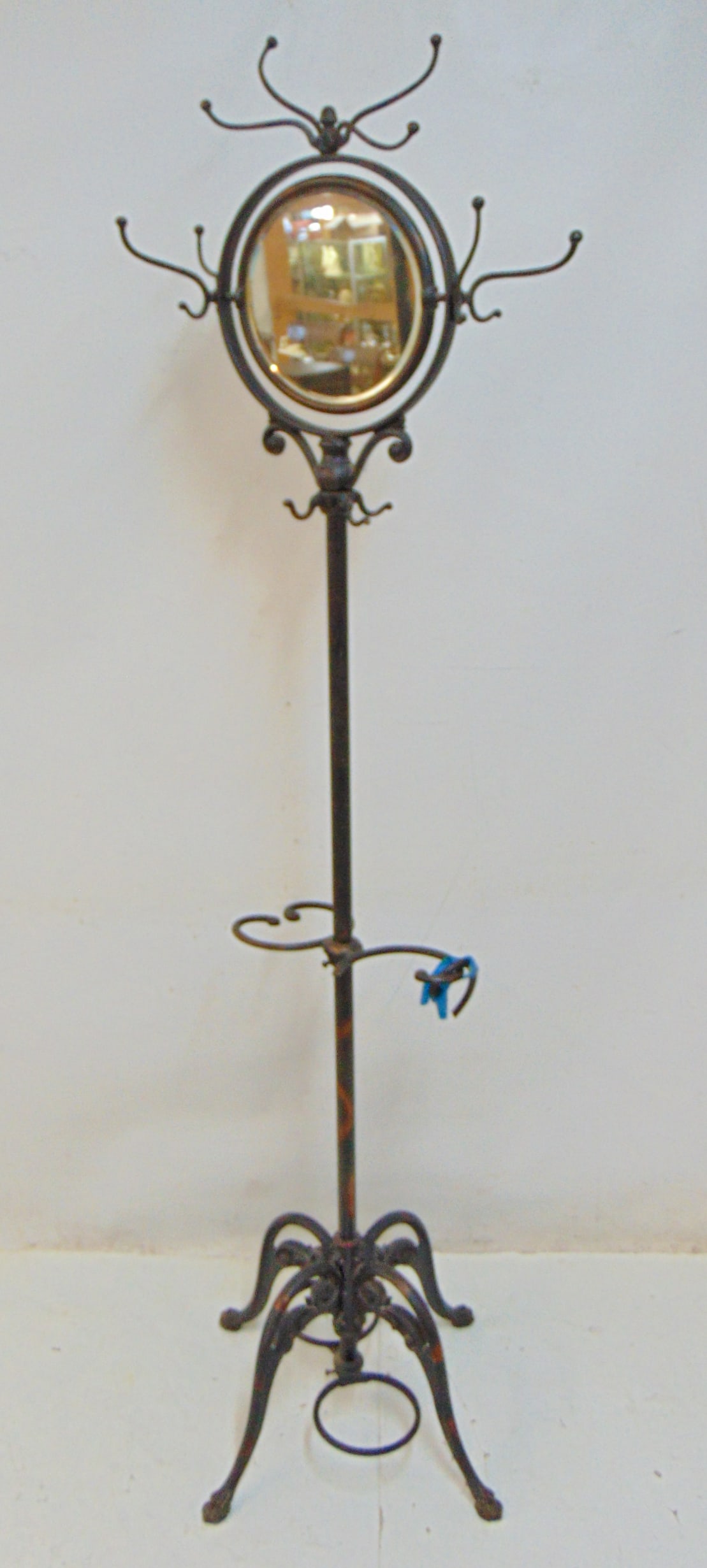 Japaned iron standing coatrack with vanity mirror, with cane, umbrella holder in base, one ring is: Japaned iron standing coatrack with vanity mirror, with cane, umbrella holder in base, one ring is broken, height is 73"
