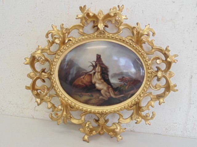 KPM porcelain plaque, elk & wolves: An oval KPM p[porcelain plaque in an elaborate gilt frame.Plaque shows an elk attacked by wolves.Condition: plaque front is in good condition, no damage visible, the back has been replaced however and