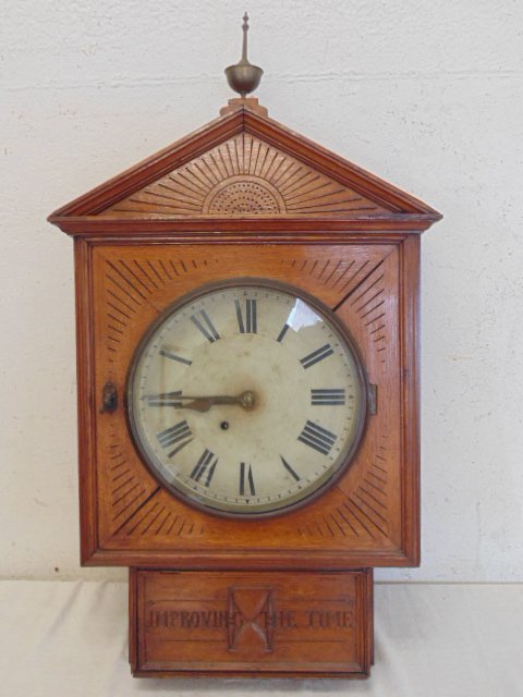 Oak wall clock, "Improving The Time": Oak wall clock, "Improving The Time", carved detail, brass finial, no maker Dimensions:36" tall Condition:minor chips on edge, light scratches