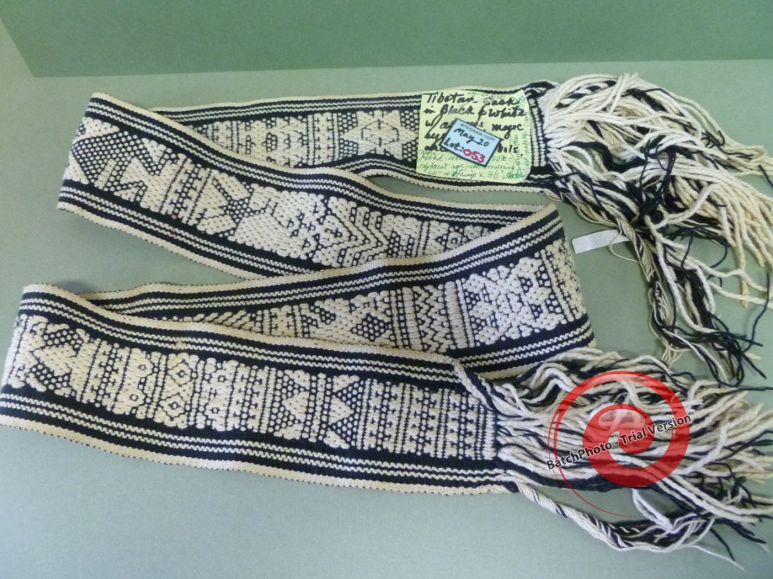 053: TIBETAN OFFICIALS SASH: Tightly woven in Black on White, it is 3-1/4" wide by 66" long (including fringe ends), and complexly designed with Stars, Magic Eyes, A Shamanic Figure with Tree headdress, Standing Snow Leopard, etc