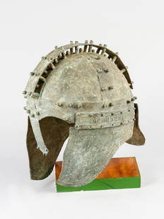 A bronze warrior helmet: A bronze or copper warrior helmet in ancient Greek or Mediterranean style; the helmet with decorated bands and knobs; in the upper centre a hightened band with knobs; on the sides ear protections and