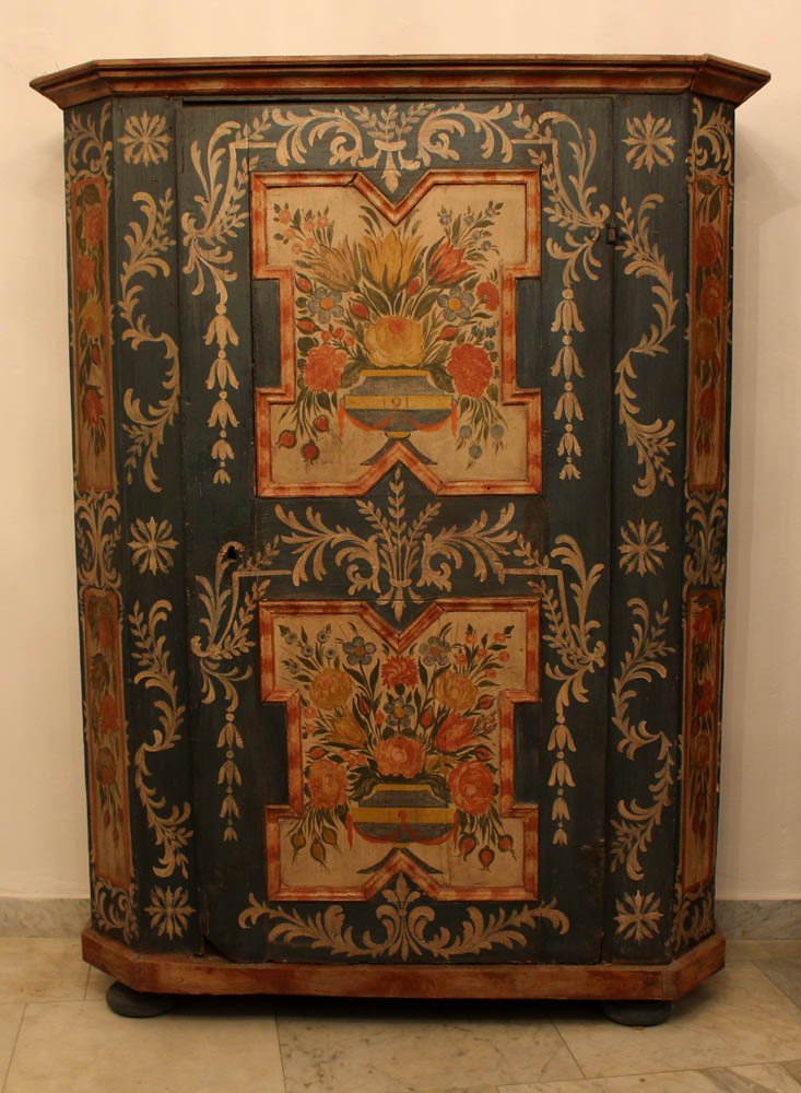 Austrian Folk Art armoir with canted borders, one door: Austrian Folk Art armoir with canted borders, one door with stepped uper and lower border, the door with two cartouches on four bun feet; pinewood painted on multicoloured floral decorations on blue a