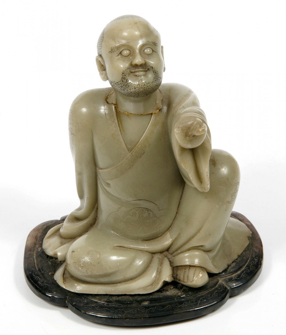 A carved green soapstone Figure, of a Chinese Begg: A carved green soapstone Figure, of a Chinese Beggar Man, with bulging eyes on a dark hardstone base, 5" (13cms). (1)