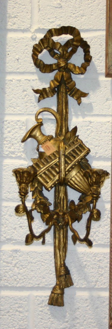 A pair of gilt two branch Wall Lights, each in the: A pair of gilt two branch Wall Lights, each in the Adams style, with ribbon bow crest above an urn pen pipes and a floral wreath issuing two candle urns terminating in tassels, 28 1/2" (72cms). (2)