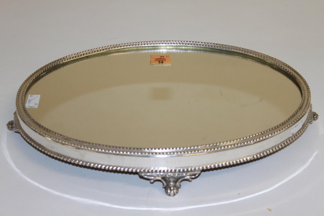 An oval silver plated table plateau or centre piece: An oval silver plated table plateau or centre piece, with mirror top on four scroll feet and a bead edge, 17" (43cms). (1).