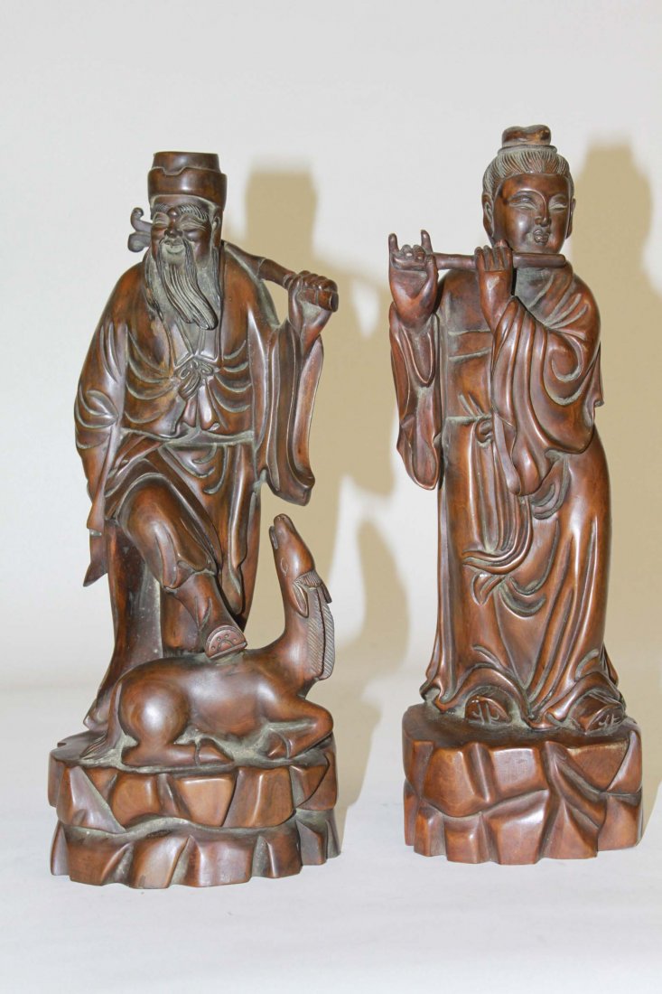 A pair of Chinese carved wooden figures, one model: A pair of Chinese carved wooden figures, one modelled as a man with one leg across a pony's back, the other, a woman playing the flute, both with inscriptions and signature verso, 14" (36cms). (2).