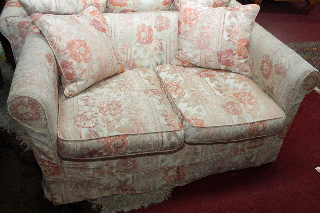 A PAIR OF MODERN TWO SEATER SETTEES, each covered in: A PAIR OF MODERN TWO SEATER SETTEES, each covered in loose floral fabric and with loose cushions, one 57in (145cm), the other 68in (173cm). (2)