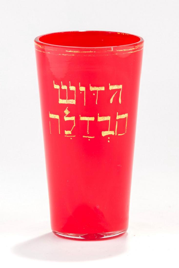A RED GLASS KIDDUSH BEAKER. Karlsbad, c. 1910.: A RED GLASS KIDDUSH BEAKER. Karlsbad, c. 1910. Decorated in gold leaf with the name of the spa resort “Karlsbad” and “Kiddush and Havdalah” in Hebrew. 3.7” tall.