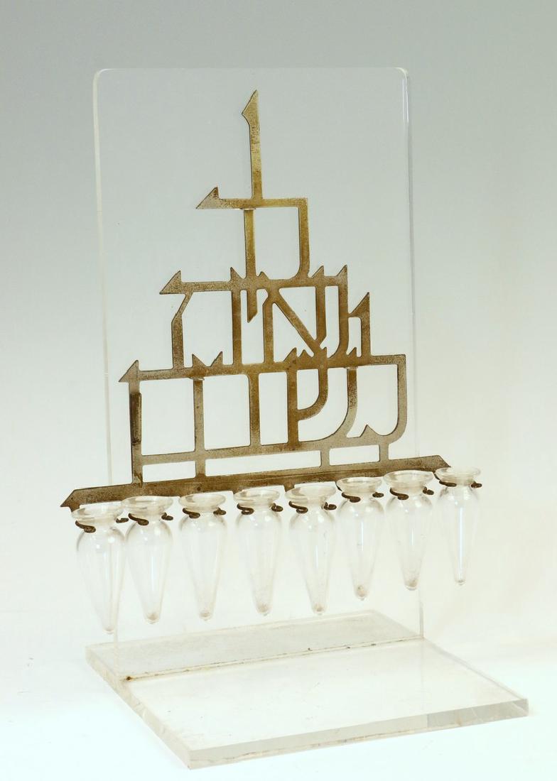 A CHANUKAH LAMP BY LUDWIG WOLPERT. Probably NY, c.: A CHANUKAH LAMP BY LUDWIG WOLPERT. Probably NY, c. 1960. With cut out hack mounted on plexiglass and glass oil receptacles. Lacking servant lamp. 10” tall.