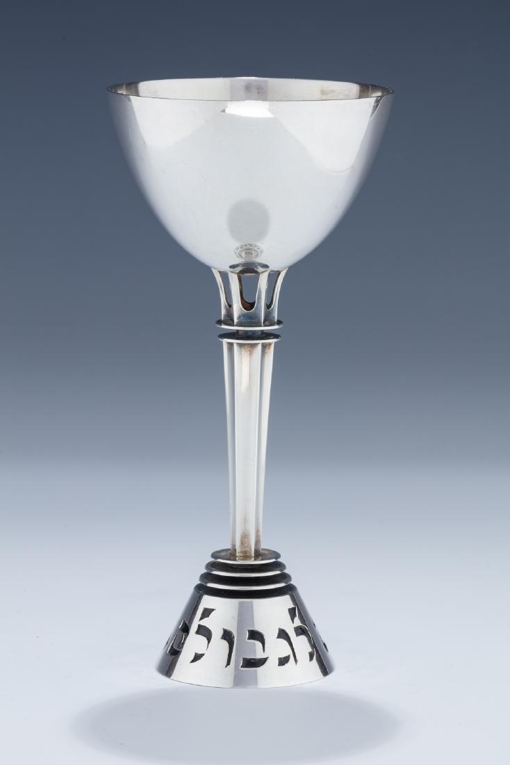 A LARGE STERLING SILVER KIDDUSH CUP BY LUDWIG WOLPERT: A LARGE STERLING SILVER KIDDUSH CUP BY LUDWIG WOLPERT FOR THE JUDAIC HERITAGE SOCIETY NUMBER 59. Portugal, 1973. On round base with cut out letters: “AND RETURN OUR BOYS TO THE BORDERS”. U