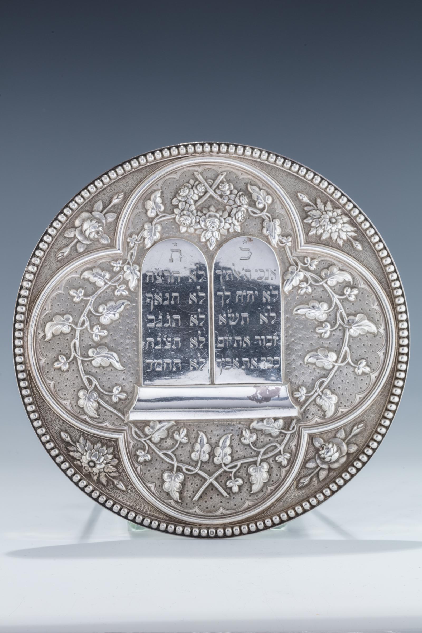 A LARGE SILVER TORAH SHIELD. France, c. 1850.: A LARGE SILVER TORAH SHIELD. France, c. 1850. Circular in form with beaded rim. The body chased with floral design. Center Decalogue chased with hand engraved lettering. With the original suspension c