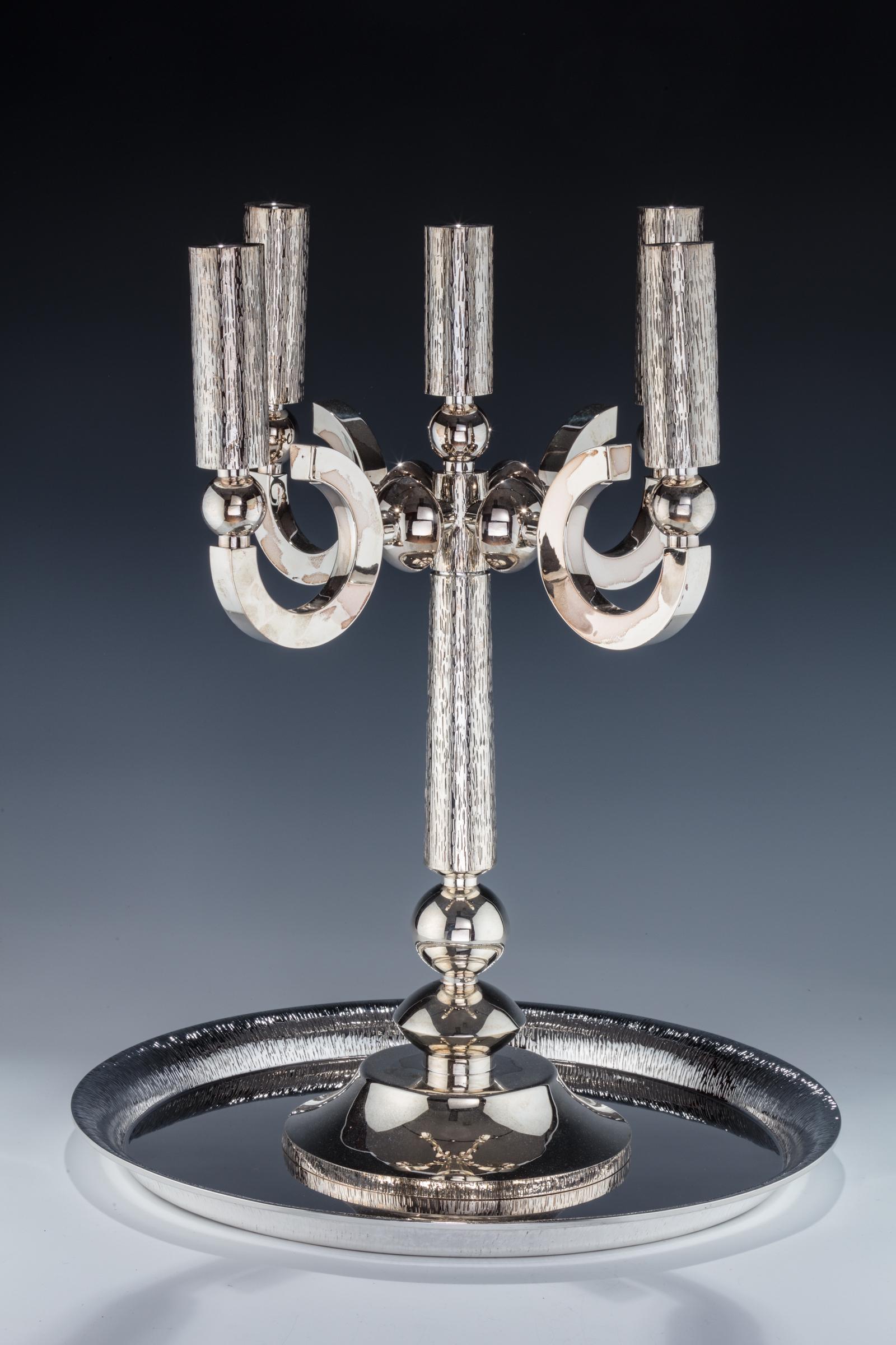 A STERLING SILVER SABBATH CANDELABRA BY CARMEL SHABI: A STERLING SILVER SABBATH CANDELABRA BY CARMEL SHABI. Israel, 1998. Round base with modern form. With a matching unsigned tray. 19” tall candelabra, 16” wide tray.