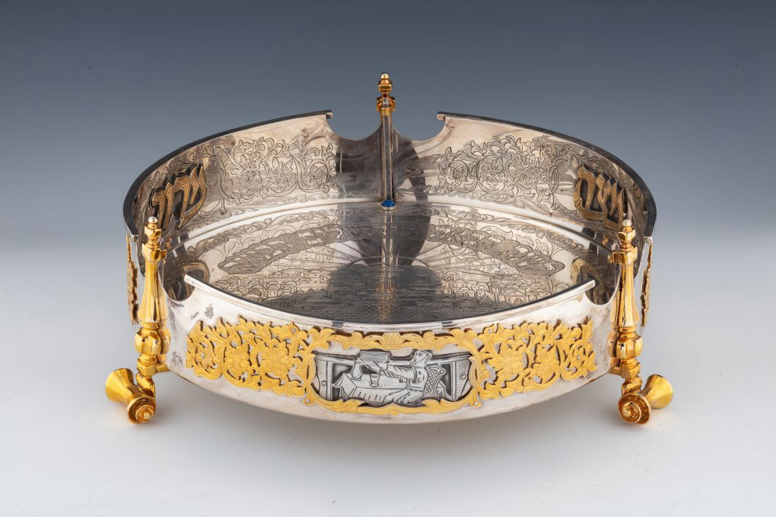 A LARGE ROUND STERLING SILVER AND 18K MATZAH HOLDER BY: A LARGE ROUND STERLING SILVER AND 18K MATZAH HOLDER BY YAAKOV DAVIDOFF. Israel, 2003. On three scrolling supports. The inside is engraved with ?NEXT YEAR IN JERUSALEM? (in Hebrew) and Old City scenes.